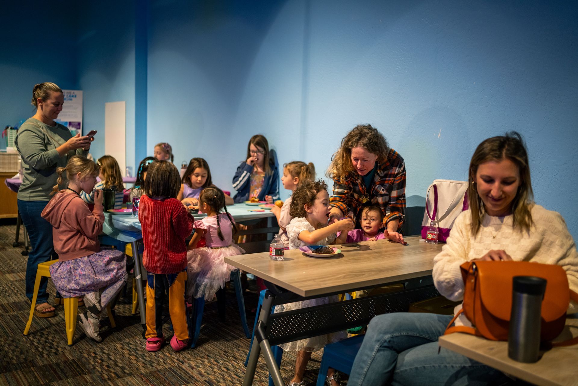 Children and adults sitting at tables in a colorful room