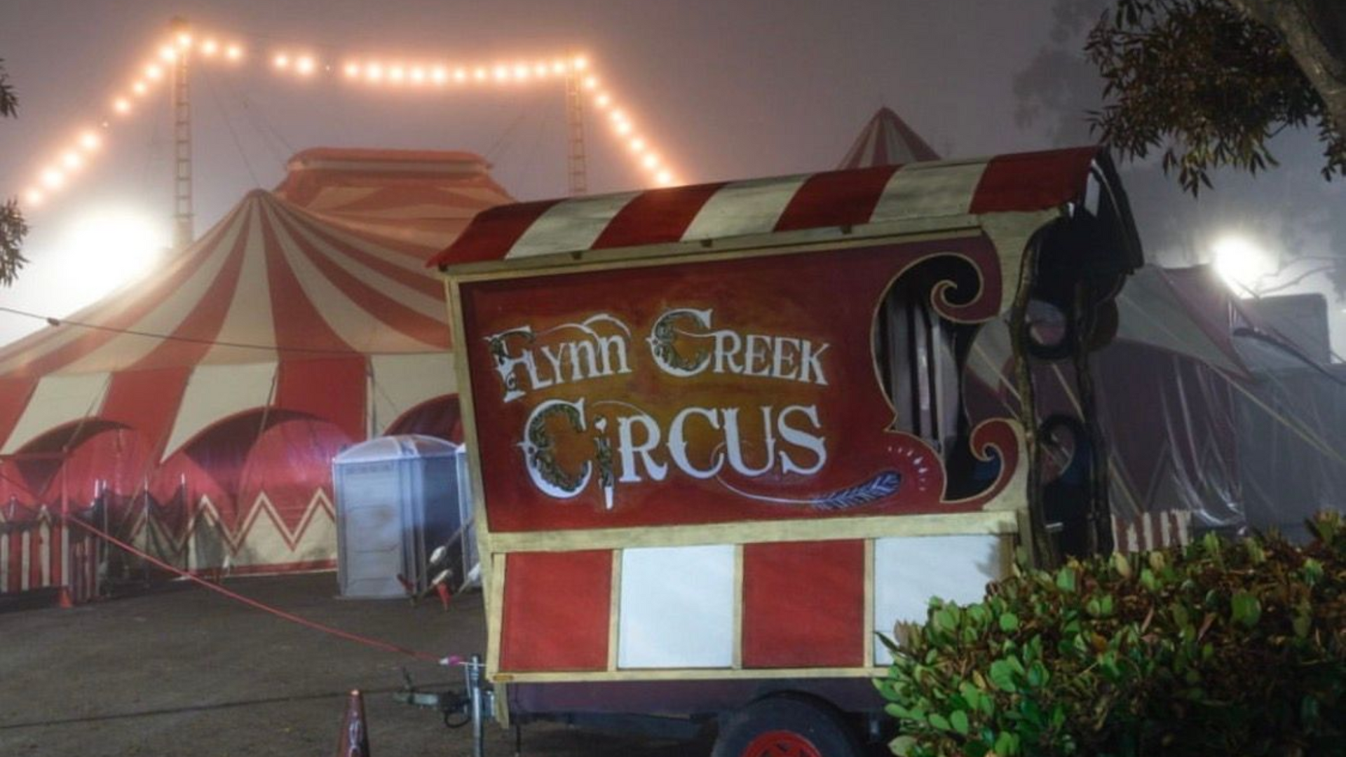 Circus entrance sign with red-and-white tent under glowing lights at dusk