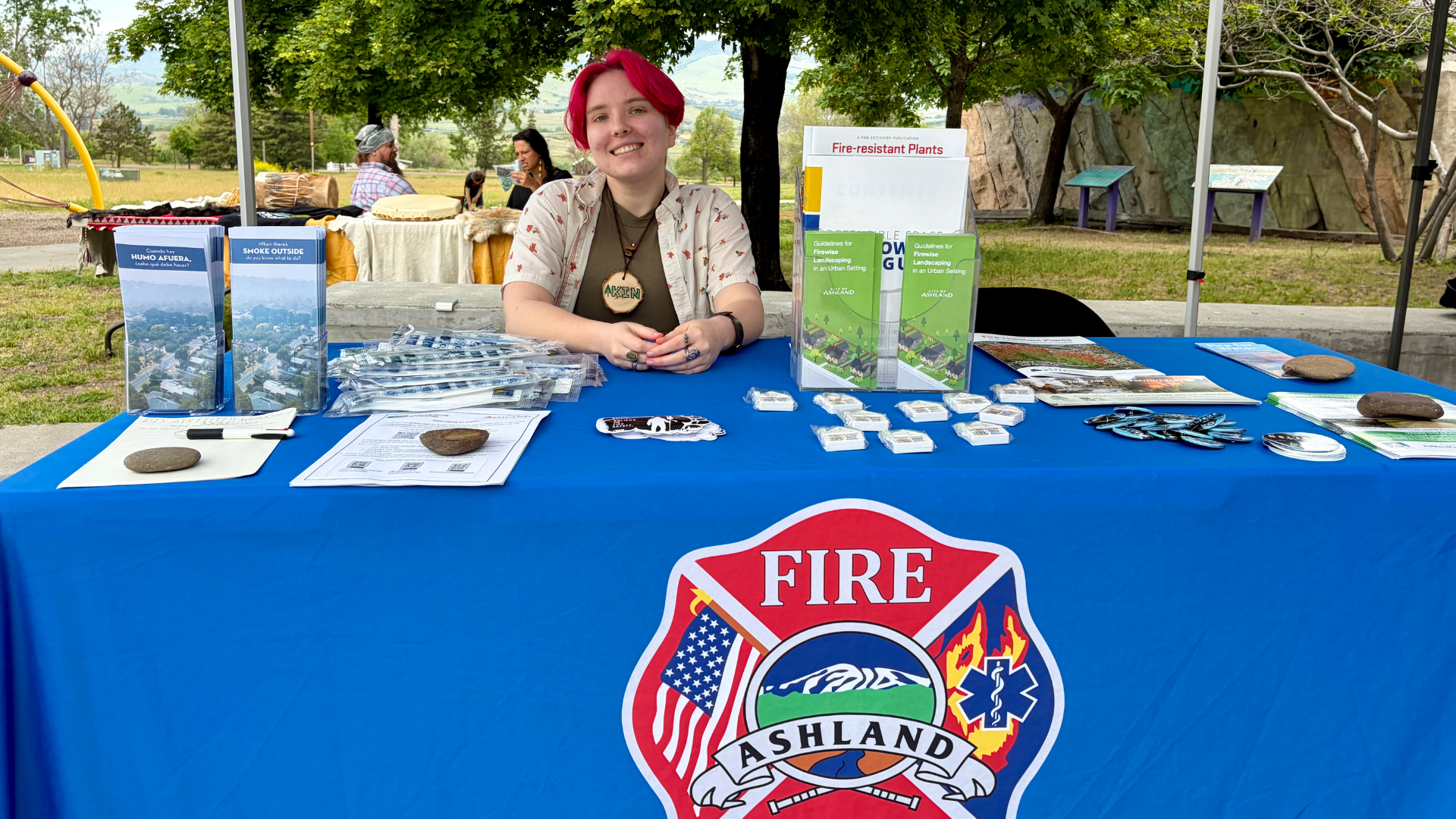 A representative from Ashland Fire and Rescue sits at an information table at Sparking Action