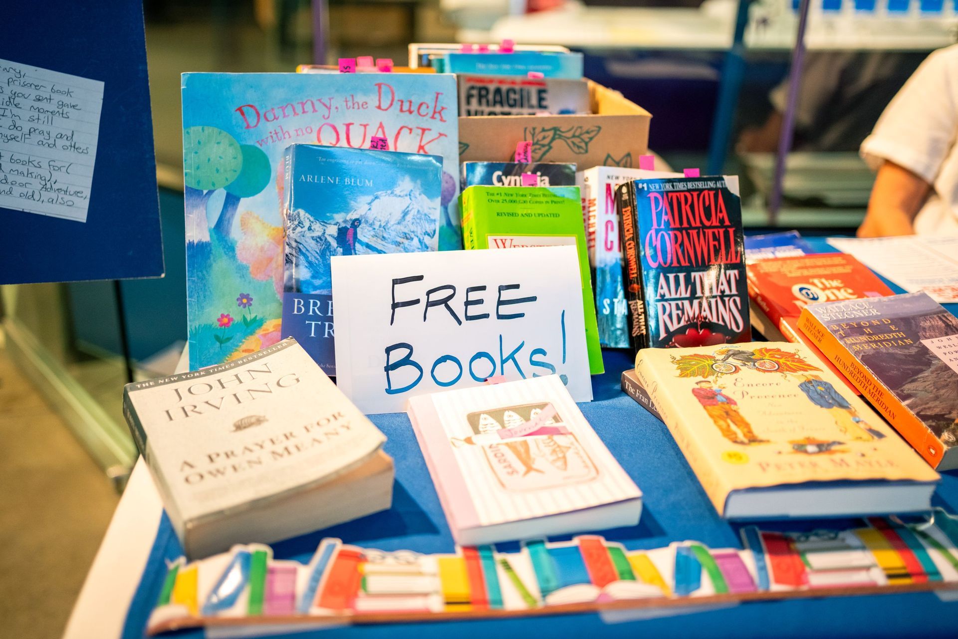 Free books displayed on a colorful table at a book giveaway booth.