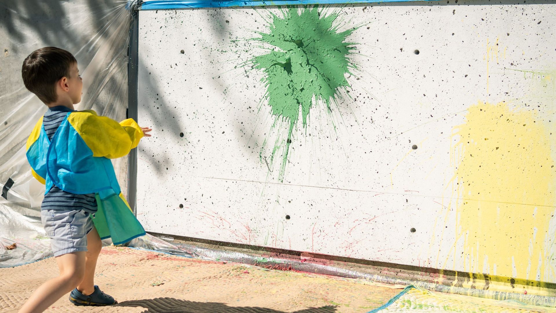 Child throwing a paint balloon at a wall