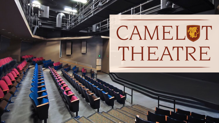 Camelot Theatre auditorium with rows of red and blue seats and a large stage sign