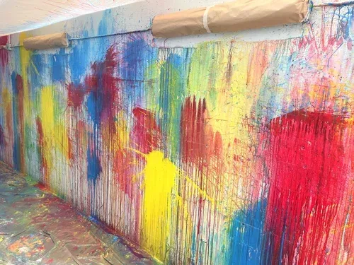 Colorful abstract mural of bright red, blue, yellow, and green paint on a wall