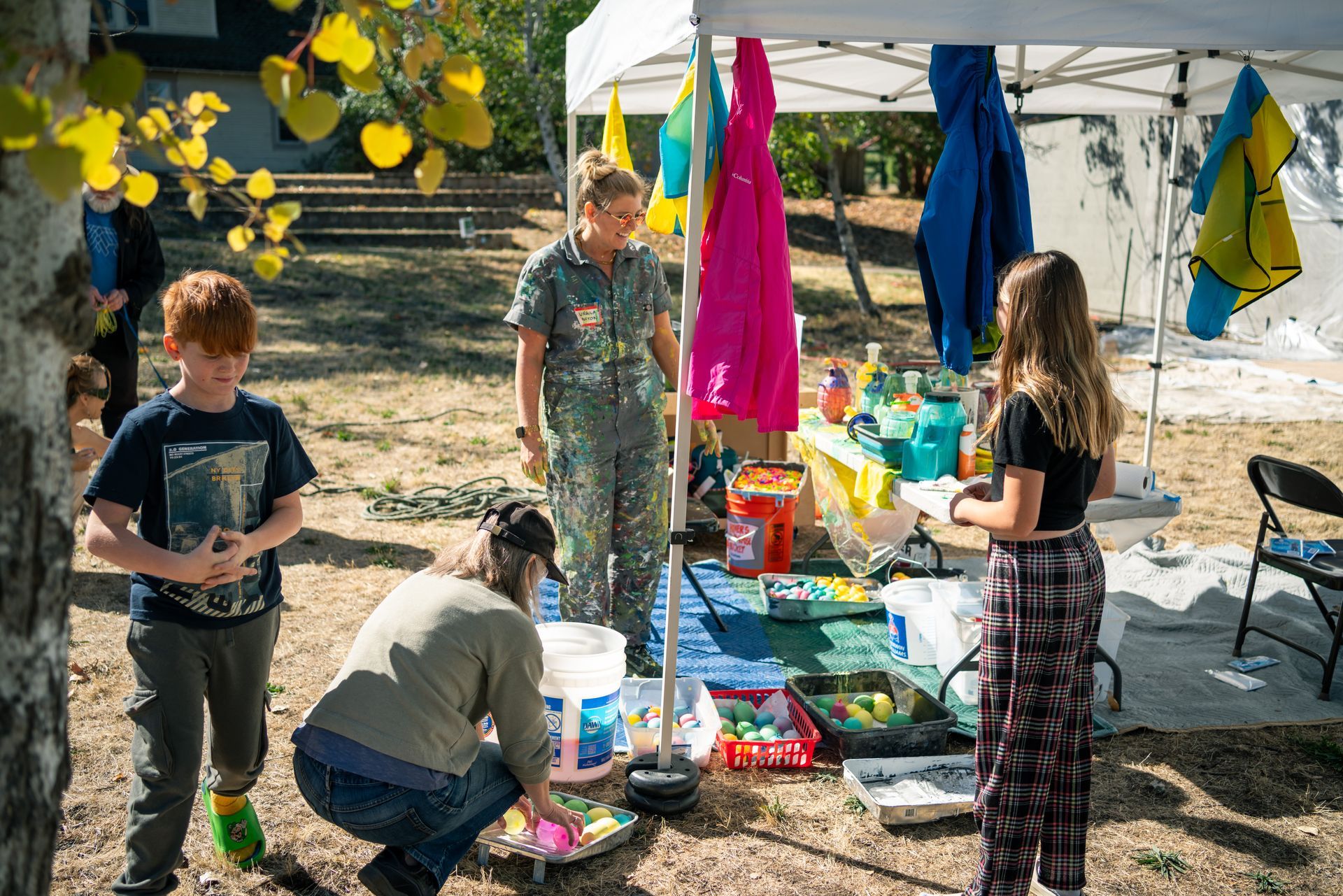 guests gather around under the canopy to collect paint balloons