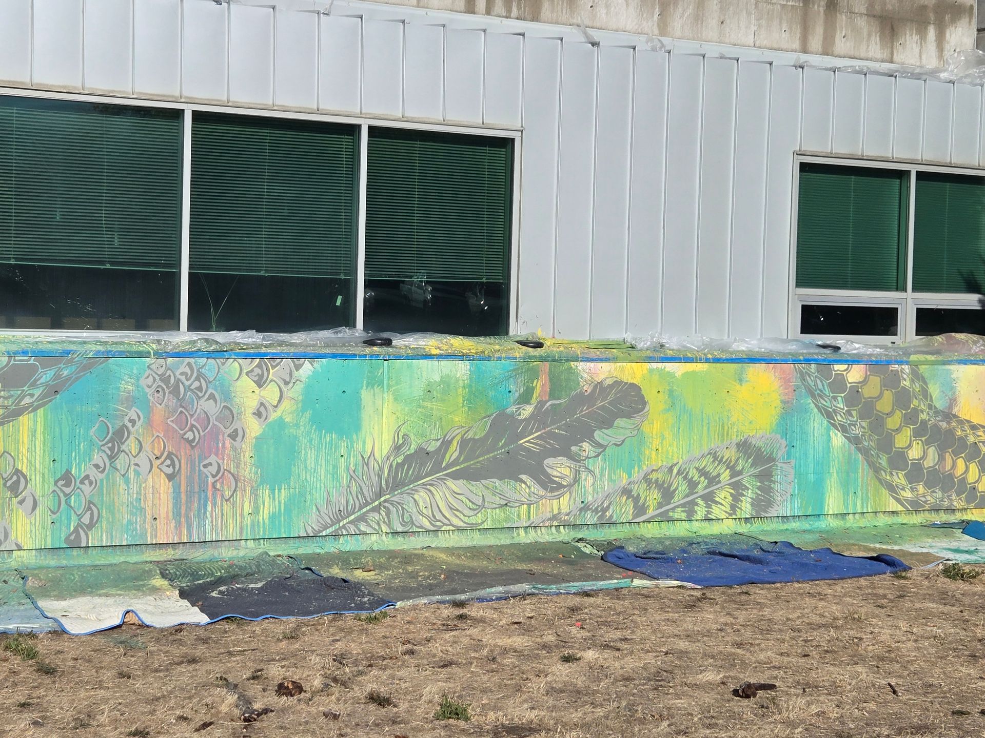 Colorful mural on a low wall with windows