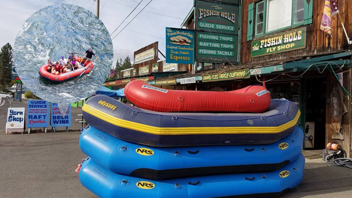 Stacked colorful rafts outside a rafting shop on a street, with a rafting scene poster nearby