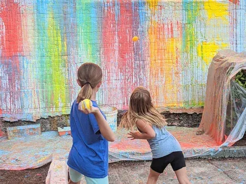 Children throwing balloons full of paint at a wall