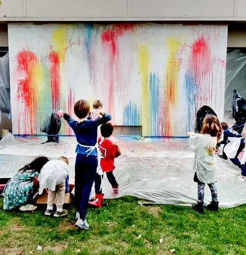 Children throwing balloons full of paint at a wall