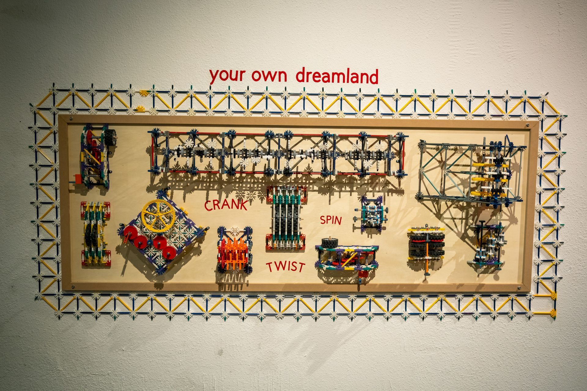 Interactive K'nex display board in a rectangular frame with colorful miniature structures and the words “Your own dreamland” above.