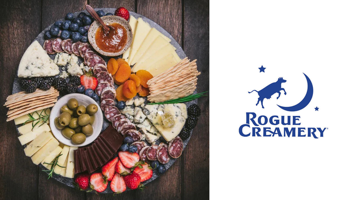 Charcuterie board with cheeses, fruit, olives and crackers beside the Rogue Creamery logo