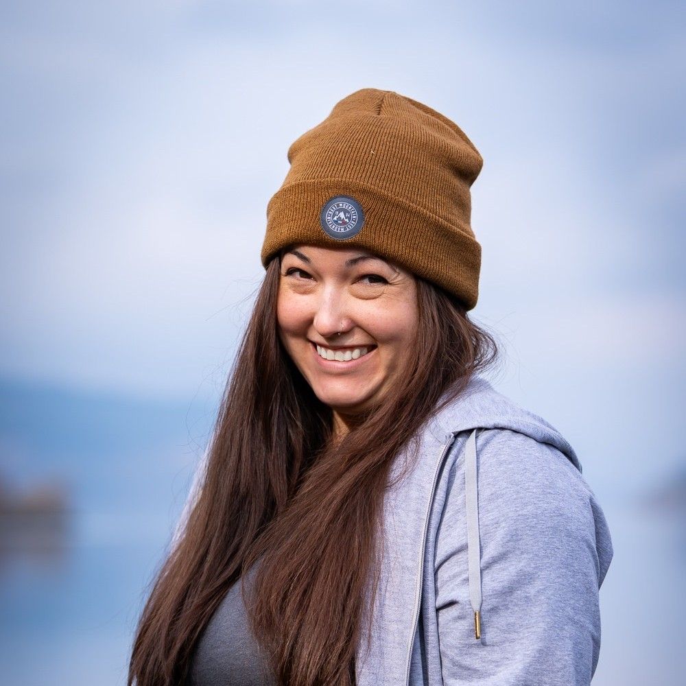 Smiling woman in a brown beanie and gray hoodie