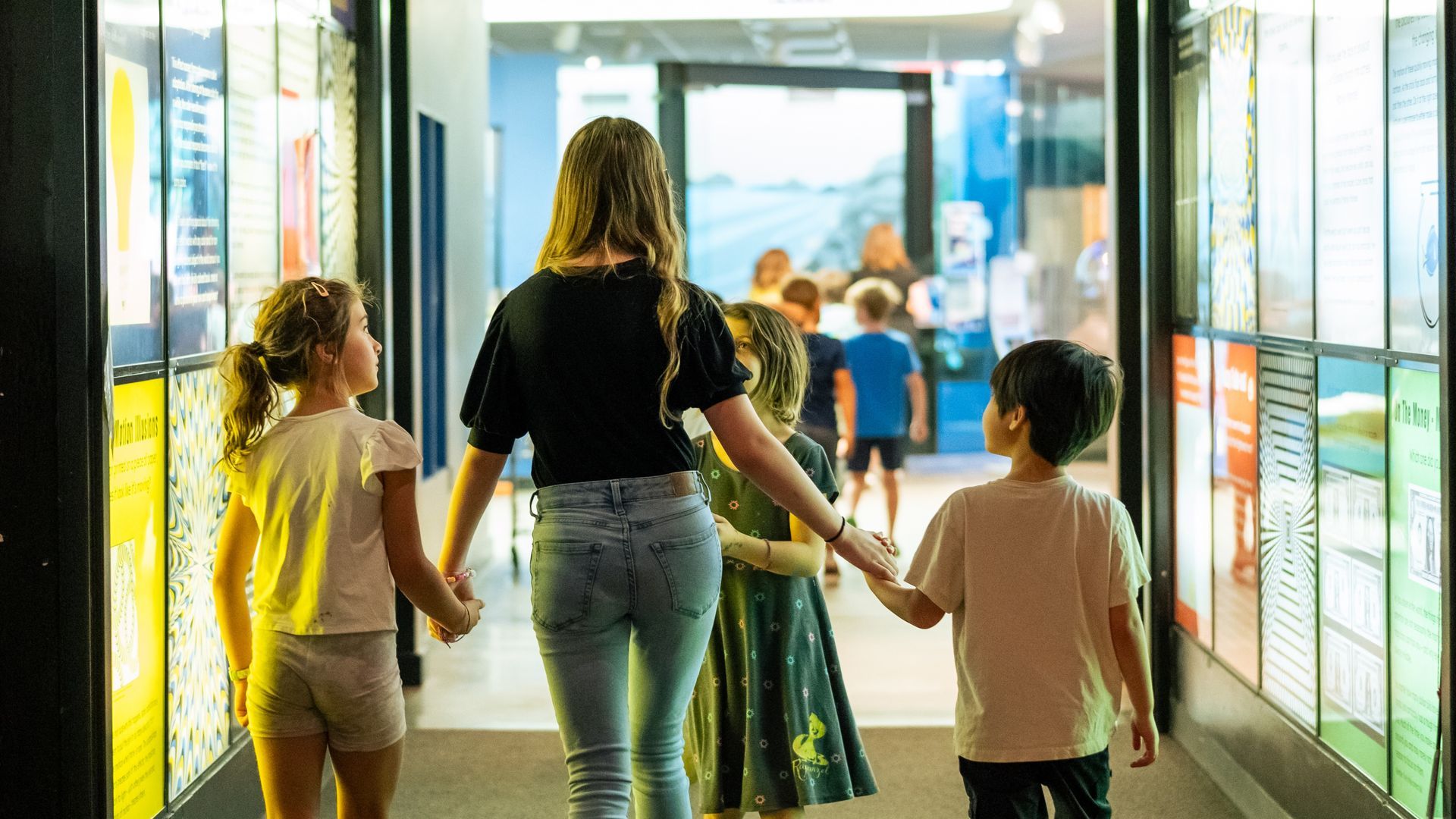 Photo of a teen girl leader 3 young kids through the hall of illusions at ScienceWorks
