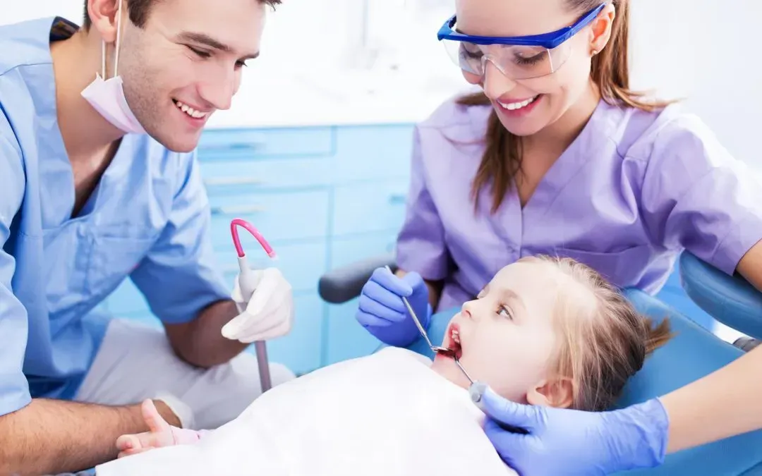 Dentist and assistant examining a young patient's teeth in a dental office.
