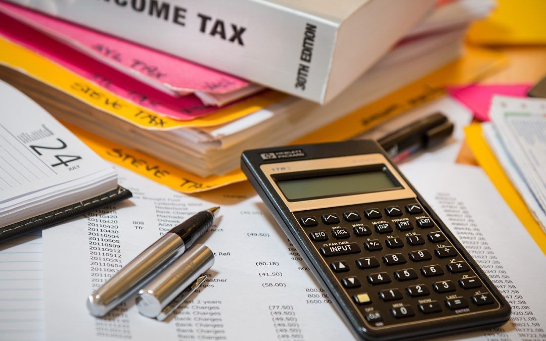 Calculator, paperwork, pen, and tax documents on a desk, representing tax preparation.