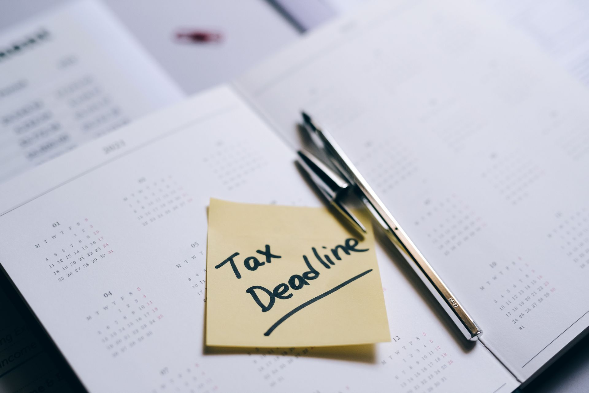 A desk calendar with Q4/year-end dates circled. A sticky note reads Tax Deadline.