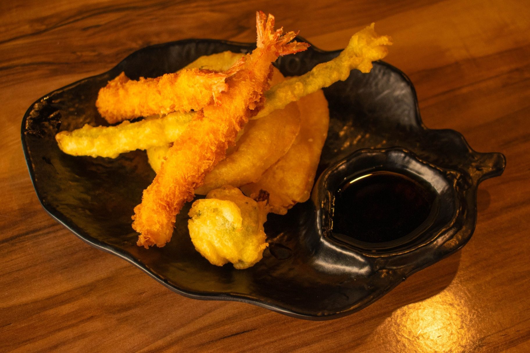 Tempura shrimp and dipping sauce on a black serving dish