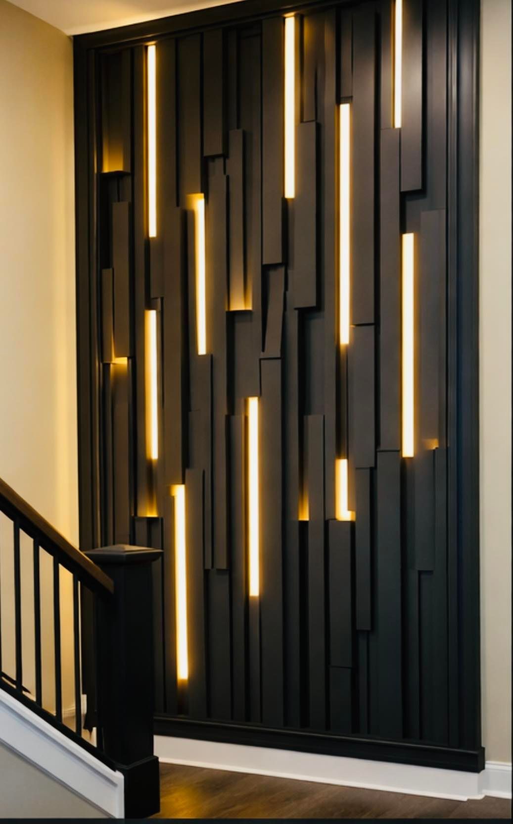 Black wall decor with vertical, glowing LED lights and abstract wood blocks next to a staircase.