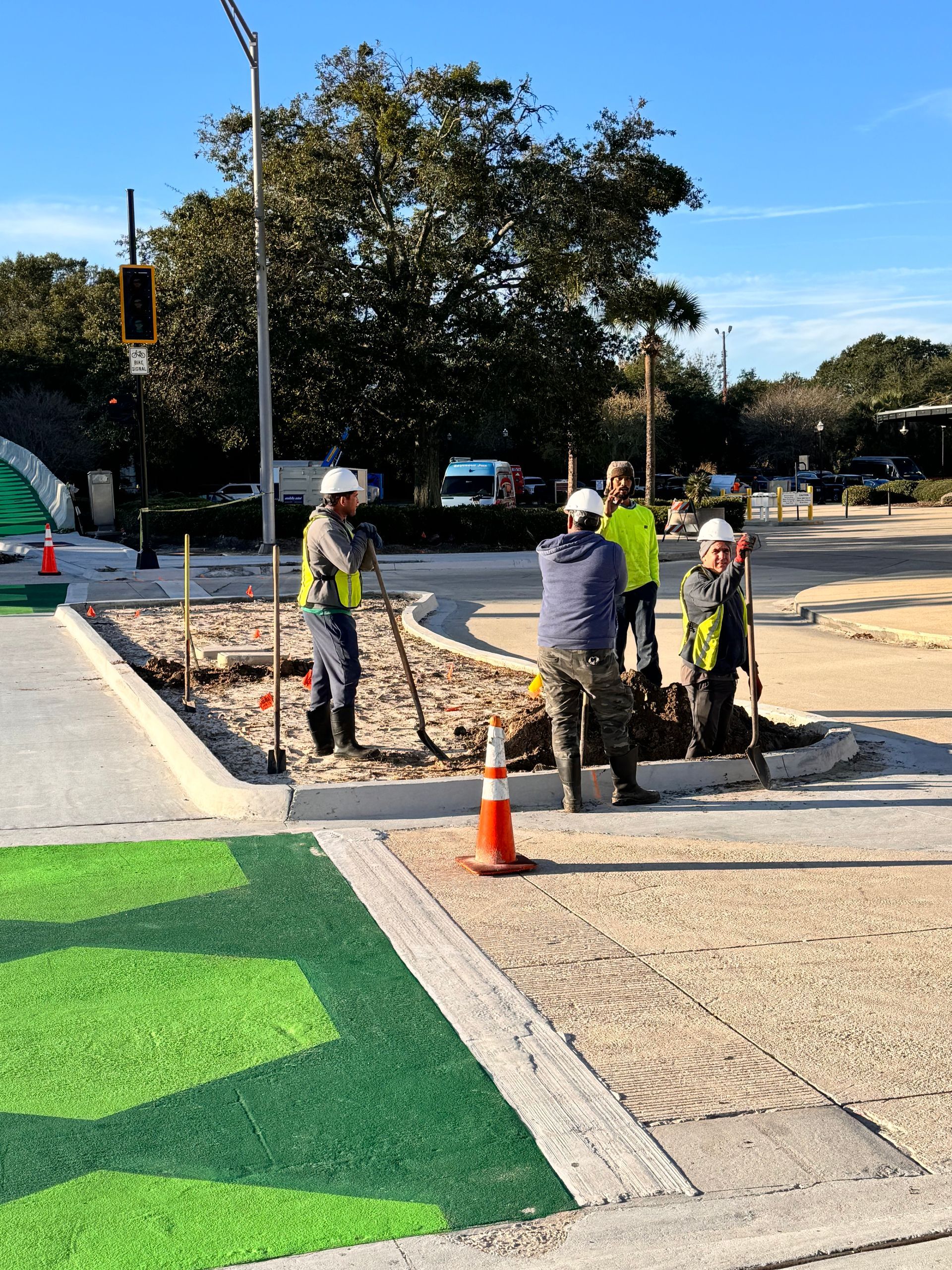 Construction workers at a curb repair site. Workers in safety vests and helmets are working on a section of the road.