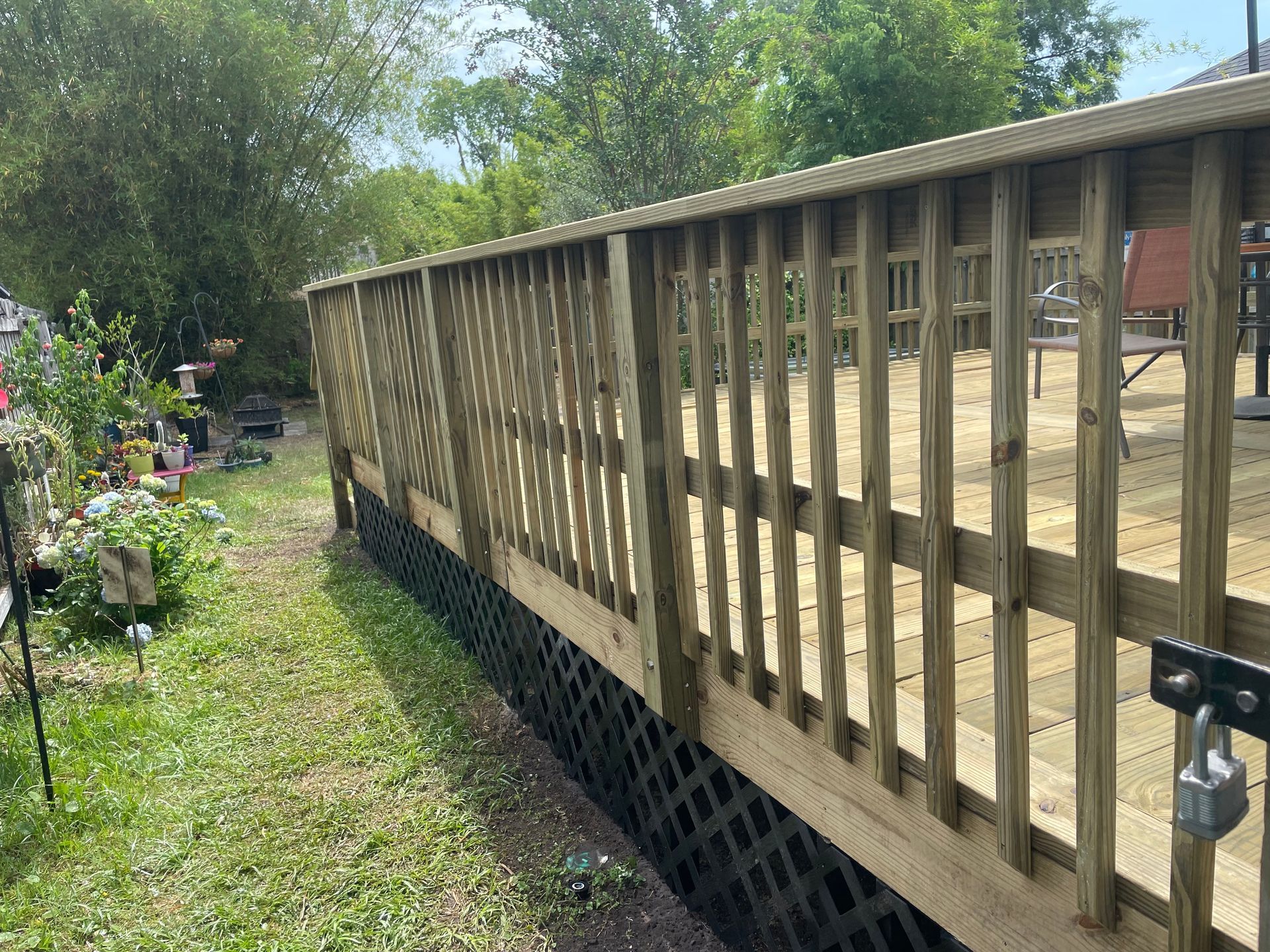 Wooden deck with lattice panels in a backyard, grass and trees in the background.