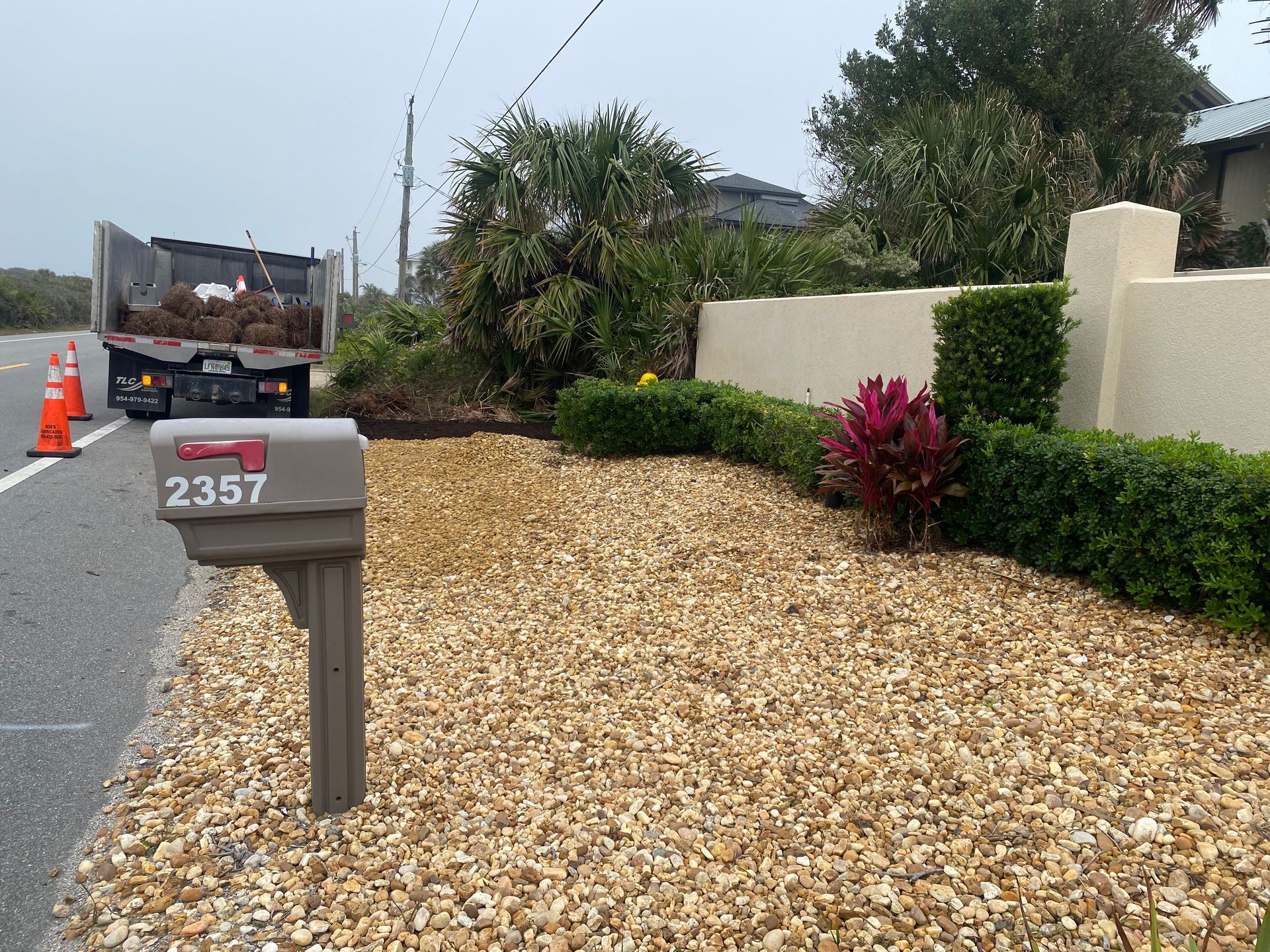 Mailbox with address 2357 beside gravel landscaping, truck in background.
