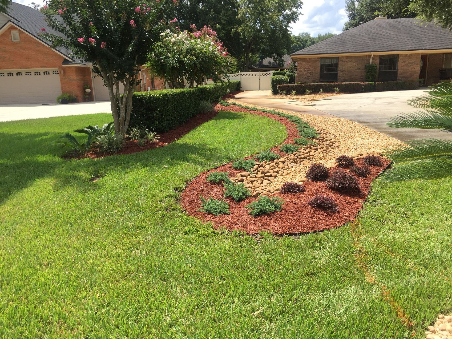 Front yard with a yin-yang pebble design on a gravel landscape near a house