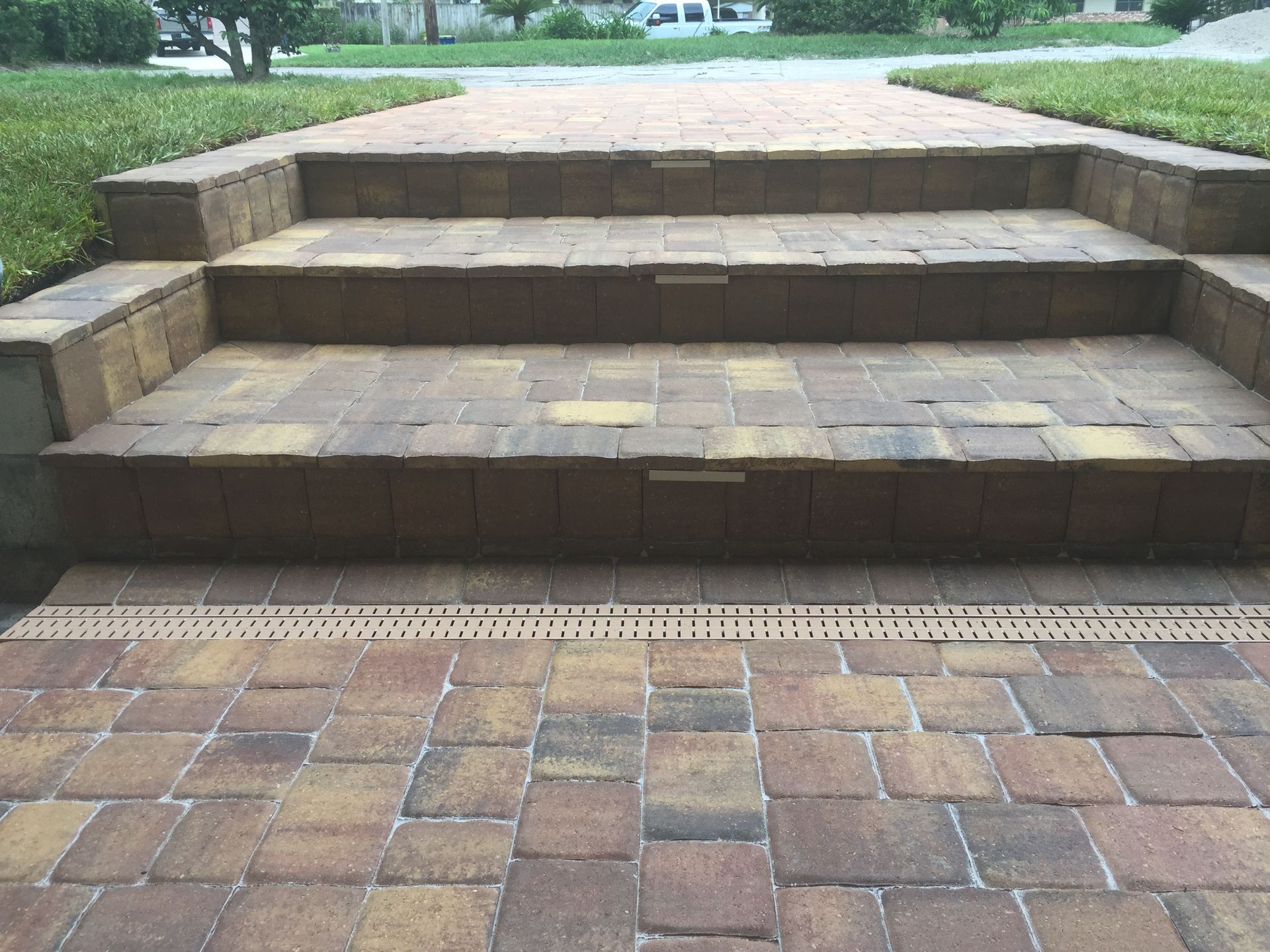 Brick steps leading up to a walkway, with grass on either side.