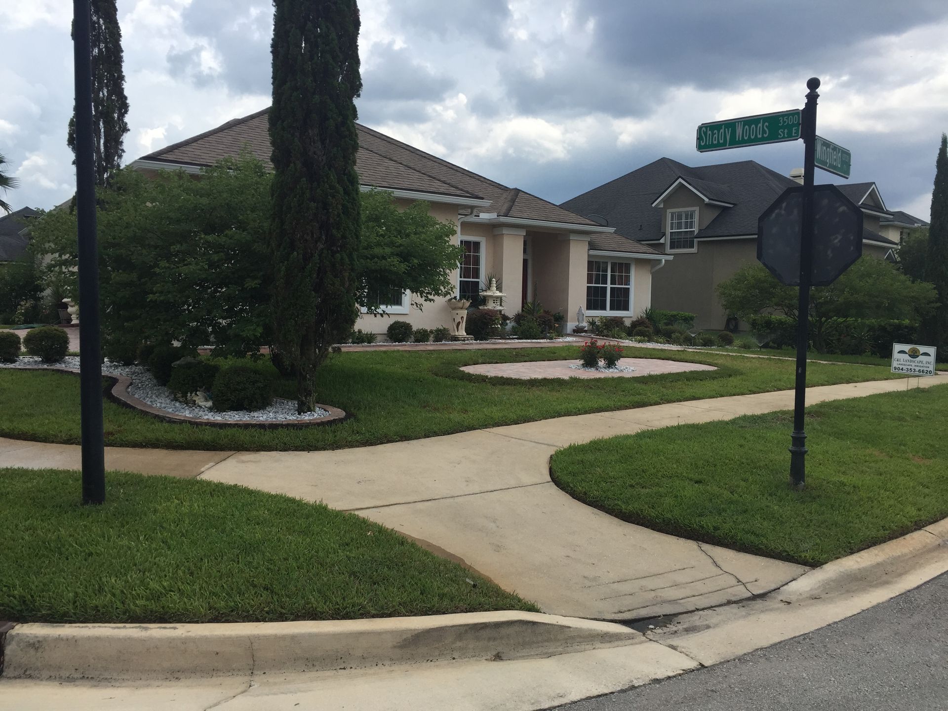 Corner lot with houses and landscaping, street signs visible.