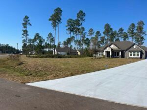 Residential area with houses, tall pine trees, and a concrete driveway.