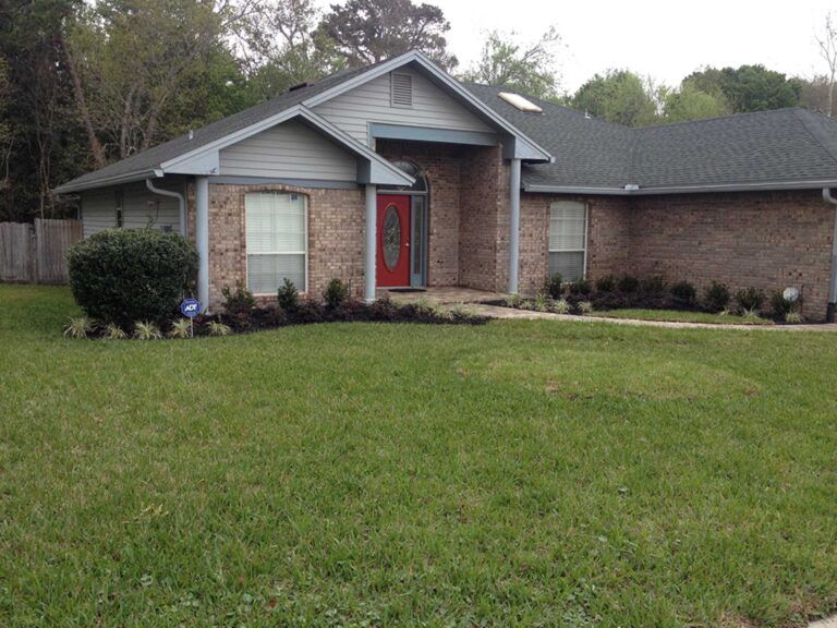 Single-story brick house with red front door and a large green lawn