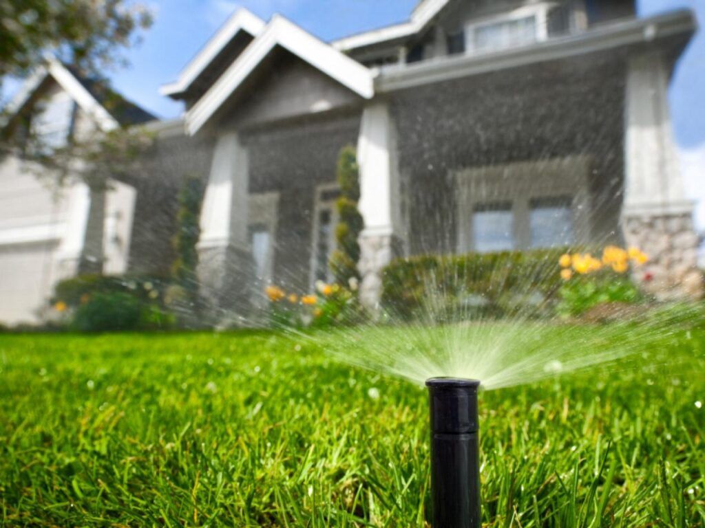 Sprinkler watering a green lawn in front of a suburban house