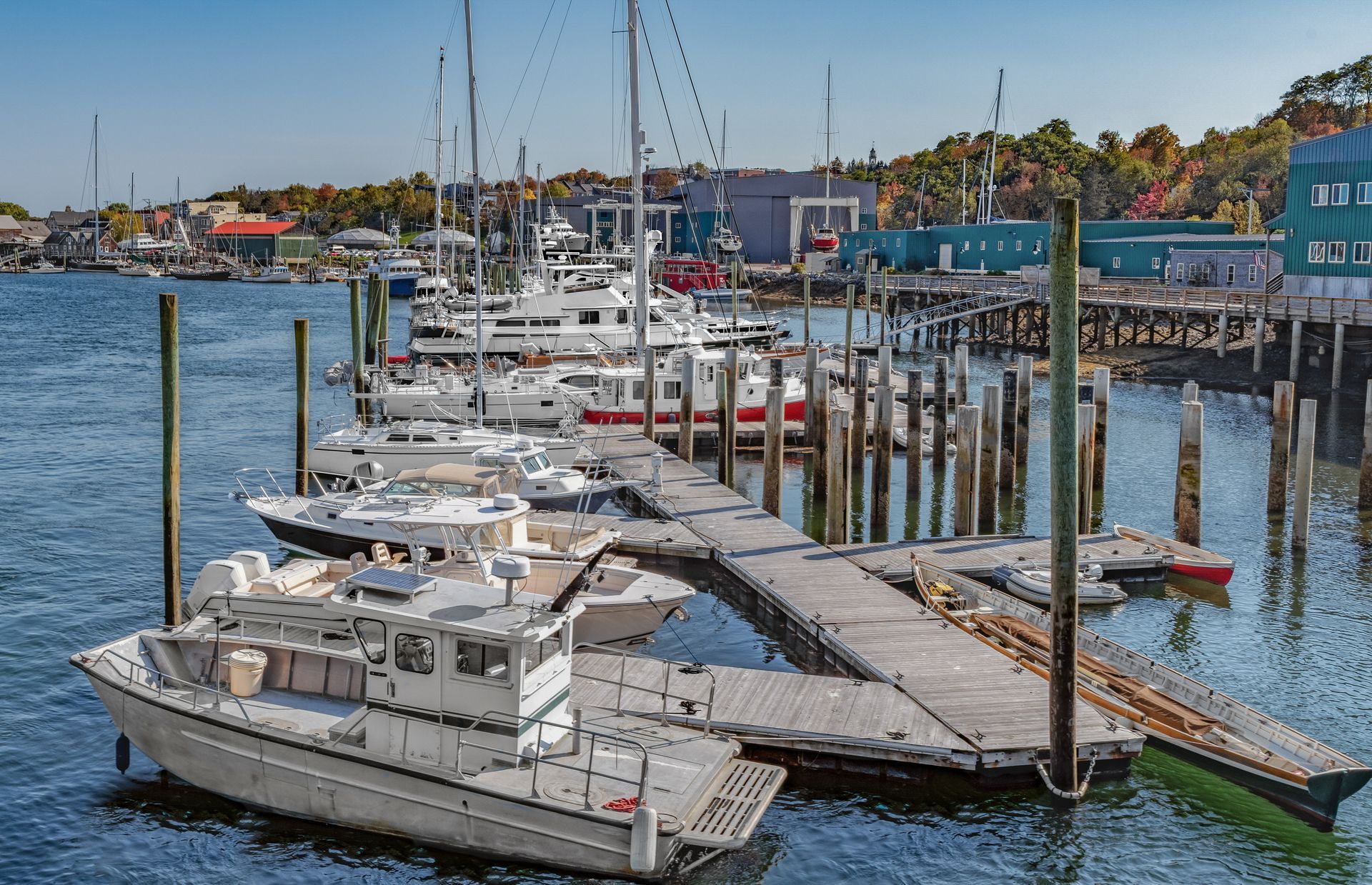 Marina dock with sailboats and motorboats moored on calm blue water under a clear sky