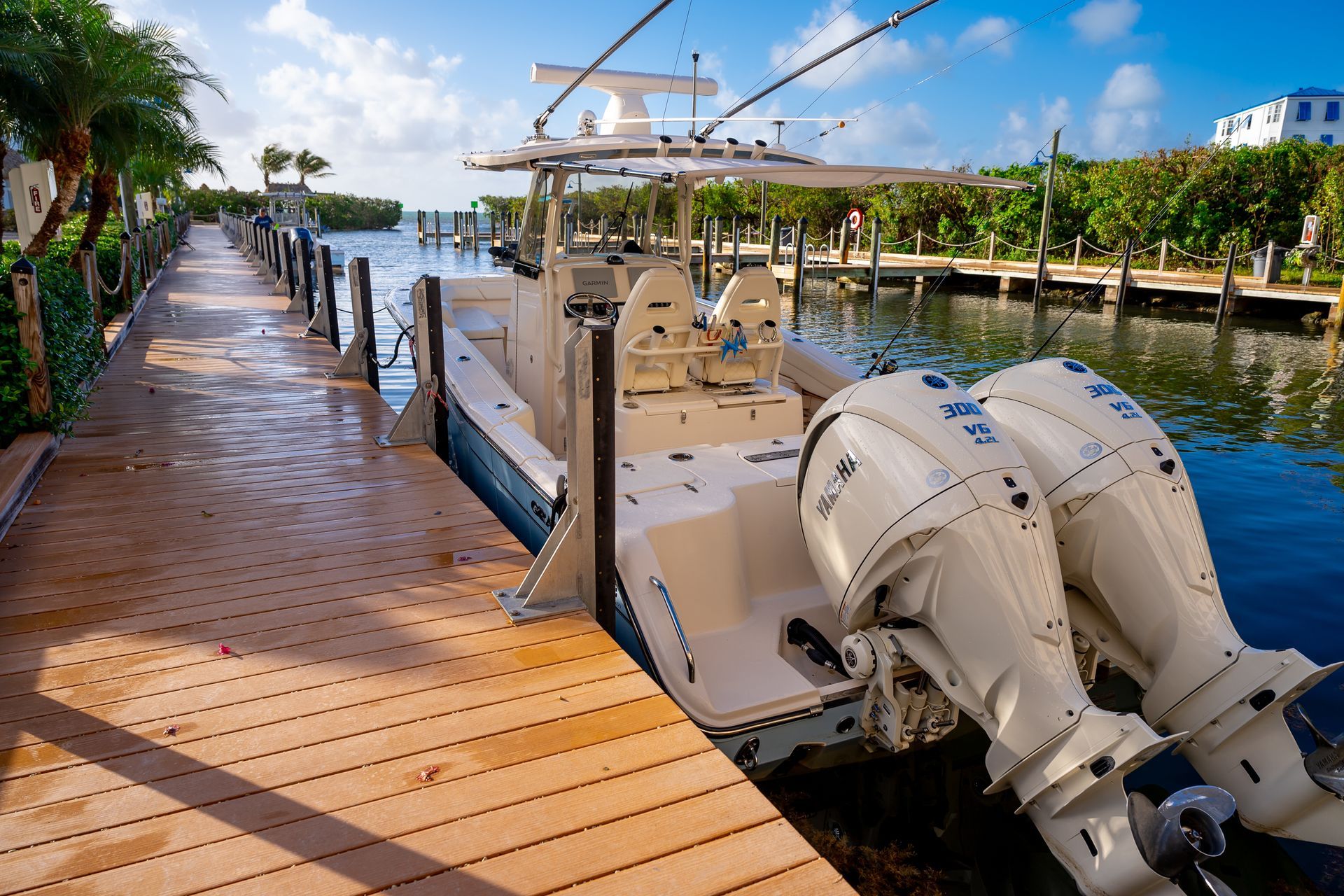 Docked motorboat beside a wooden marina walkway under a bright blue sky