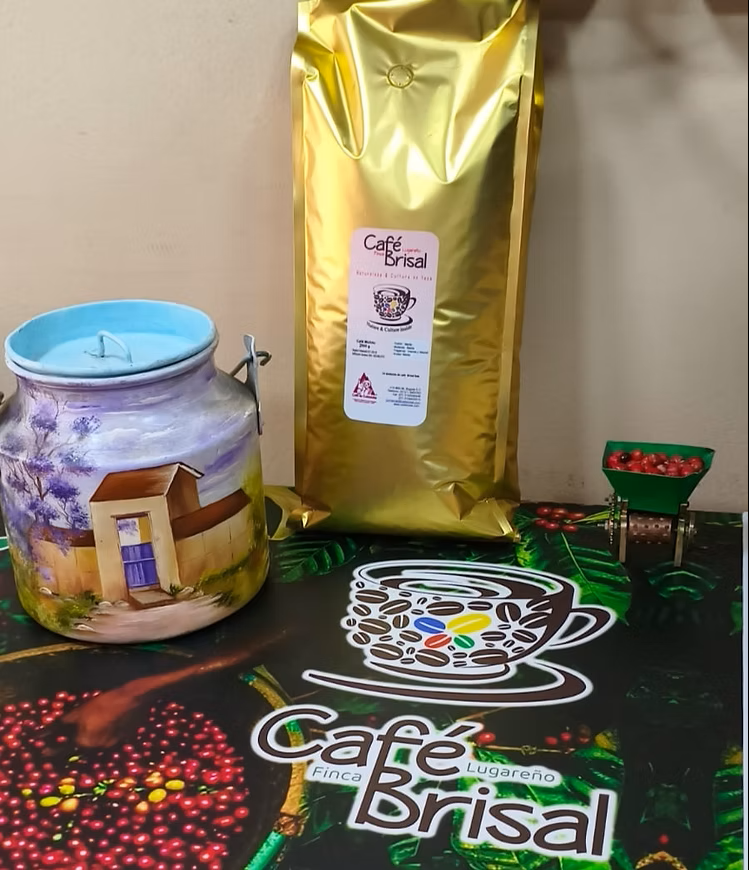 Exhibidor de café Café Brisal con bolsa dorada, frasco y tapete de la marca sobre una mesa.