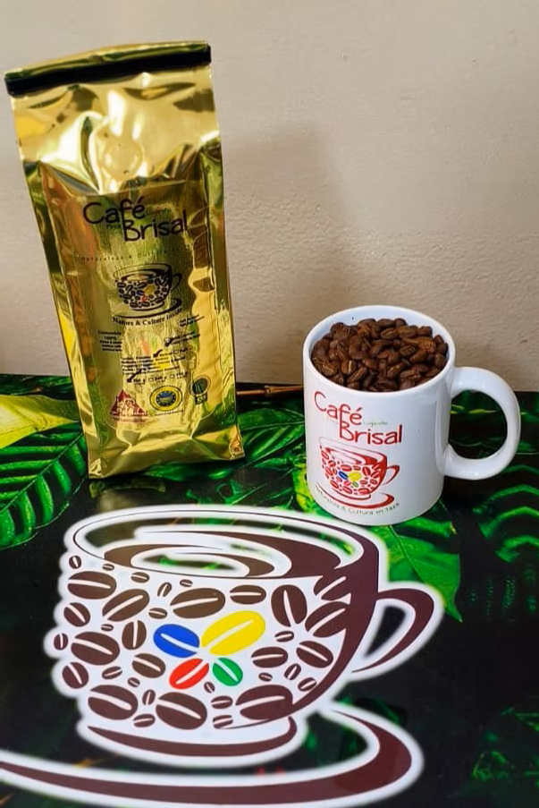 Bolsa de café dorada y taza blanca llena de granos sobre una tela estampada, junto a la imagen de una taza de café.
