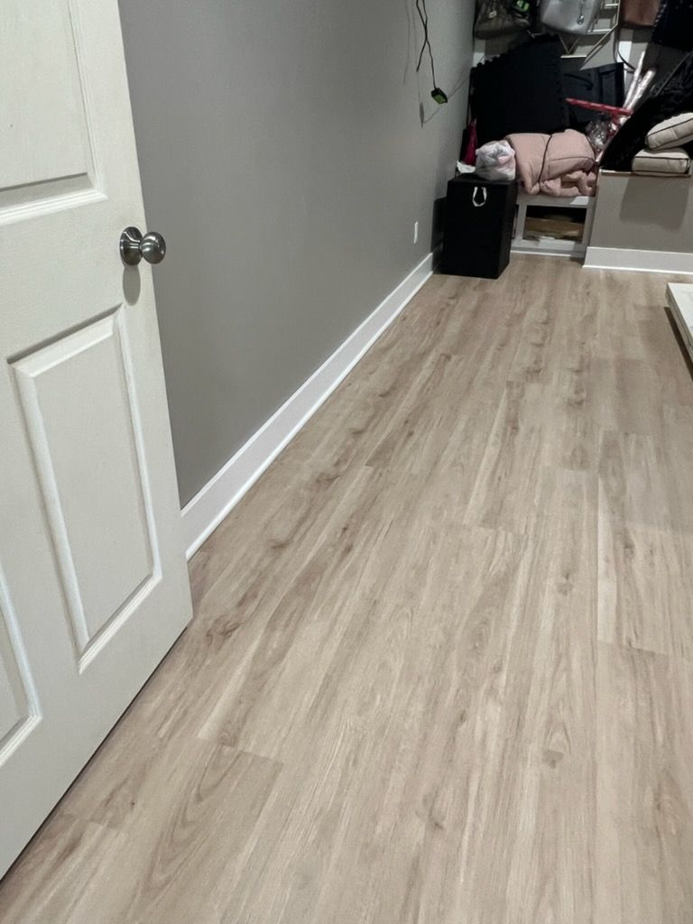 Empty hallway with light wood flooring, gray walls, and a white door.