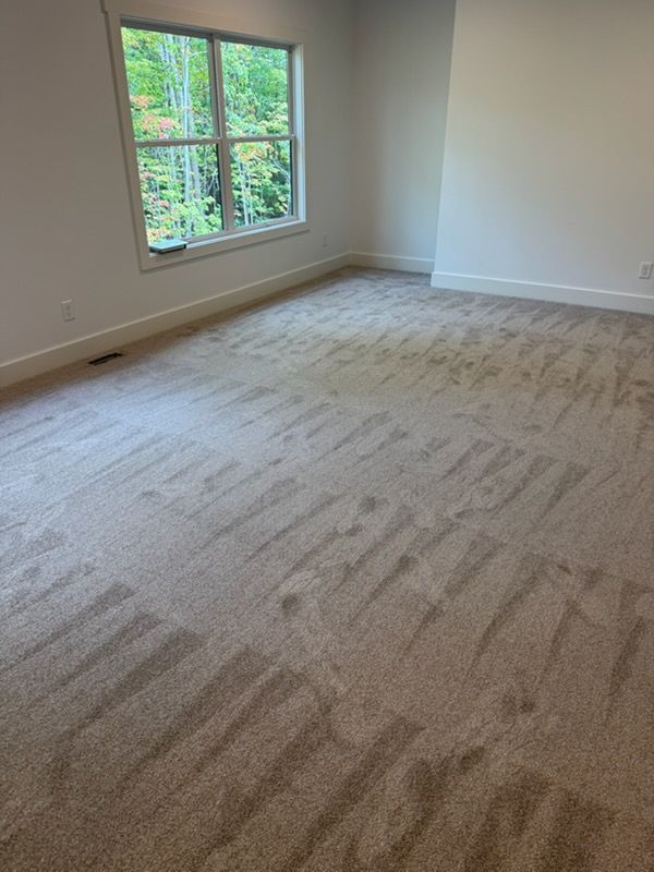 Empty beige-carpeted room with a window letting in natural light