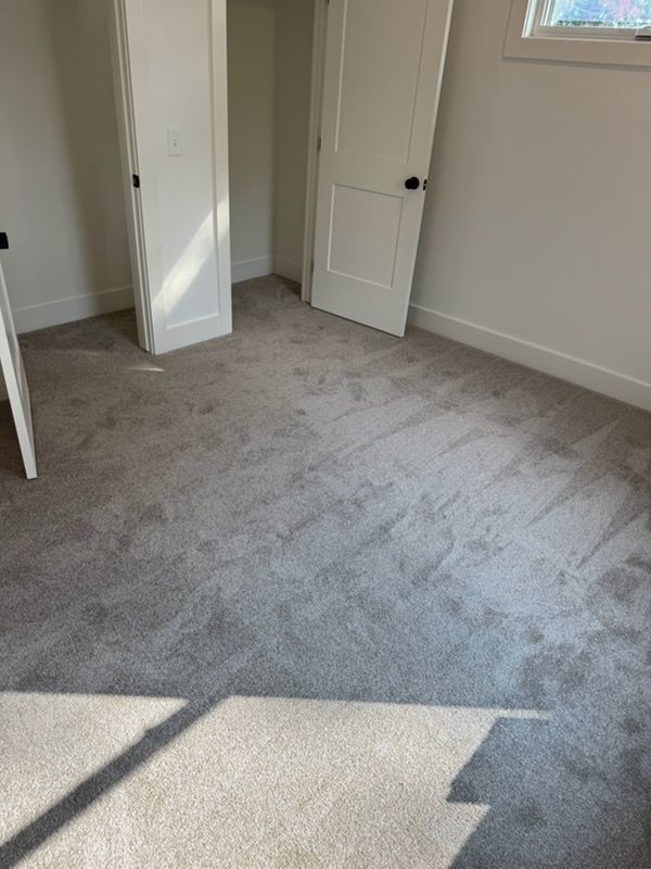 Empty beige-carpeted bedroom with open white doors and sunlight on the floor