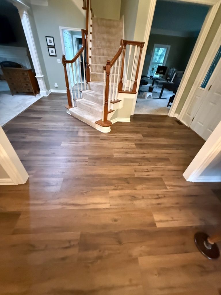 Wood-floored foyer with a curved staircase and blue walls, viewed from an open doorway