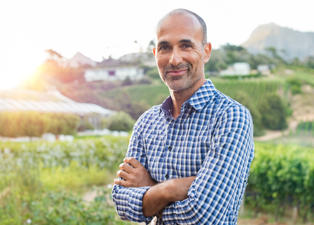 Man standing outdoors with arms crossed, smiling.
