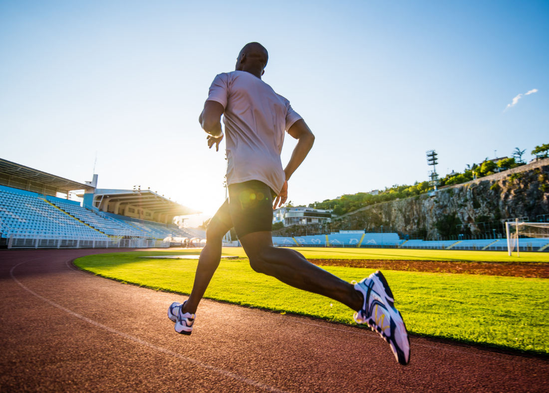 Man running on a track at sunset.