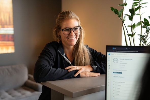 Photo of a woman smiling at a desk with a laptop