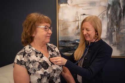 Cora Mattie adjusting a stethoscope with a patient