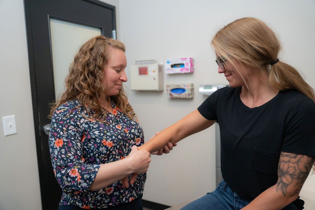 A healthcare professional examining a person's arm in a medical setting.