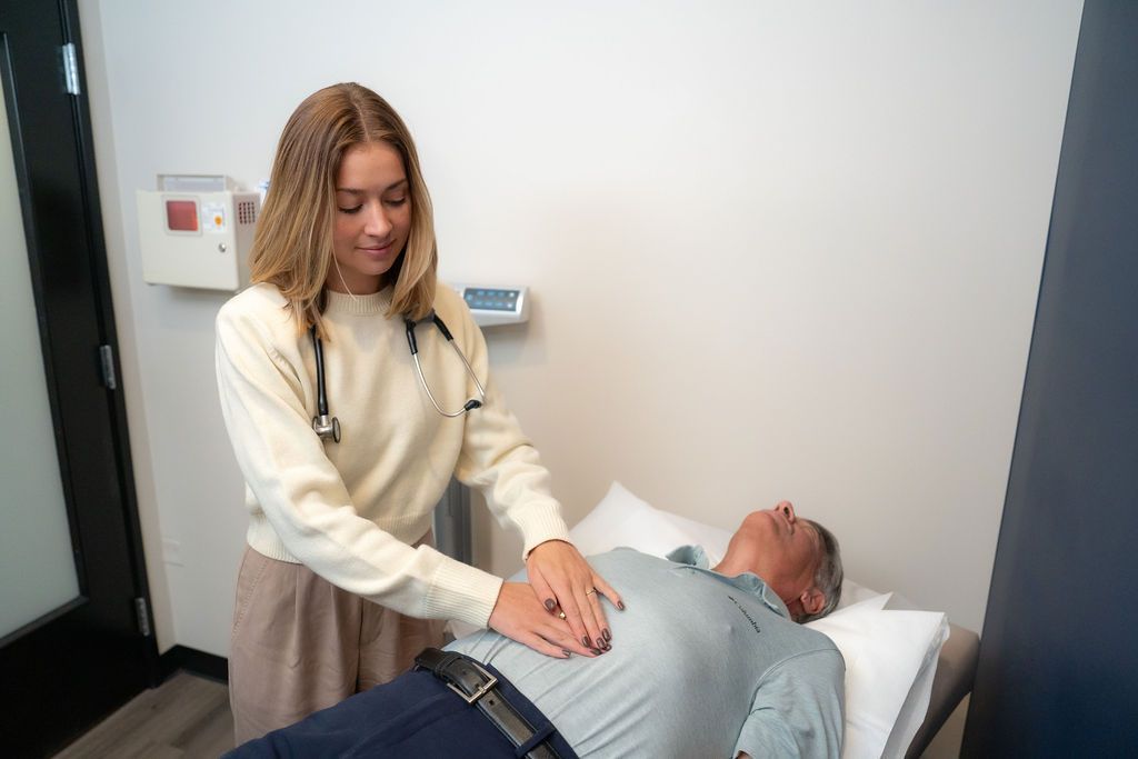 Taylor Archer attending to a male patient lying on a bed.