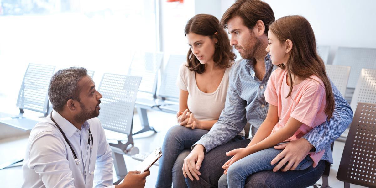 Doctor speaking with a seated family in a bright clinic waiting room