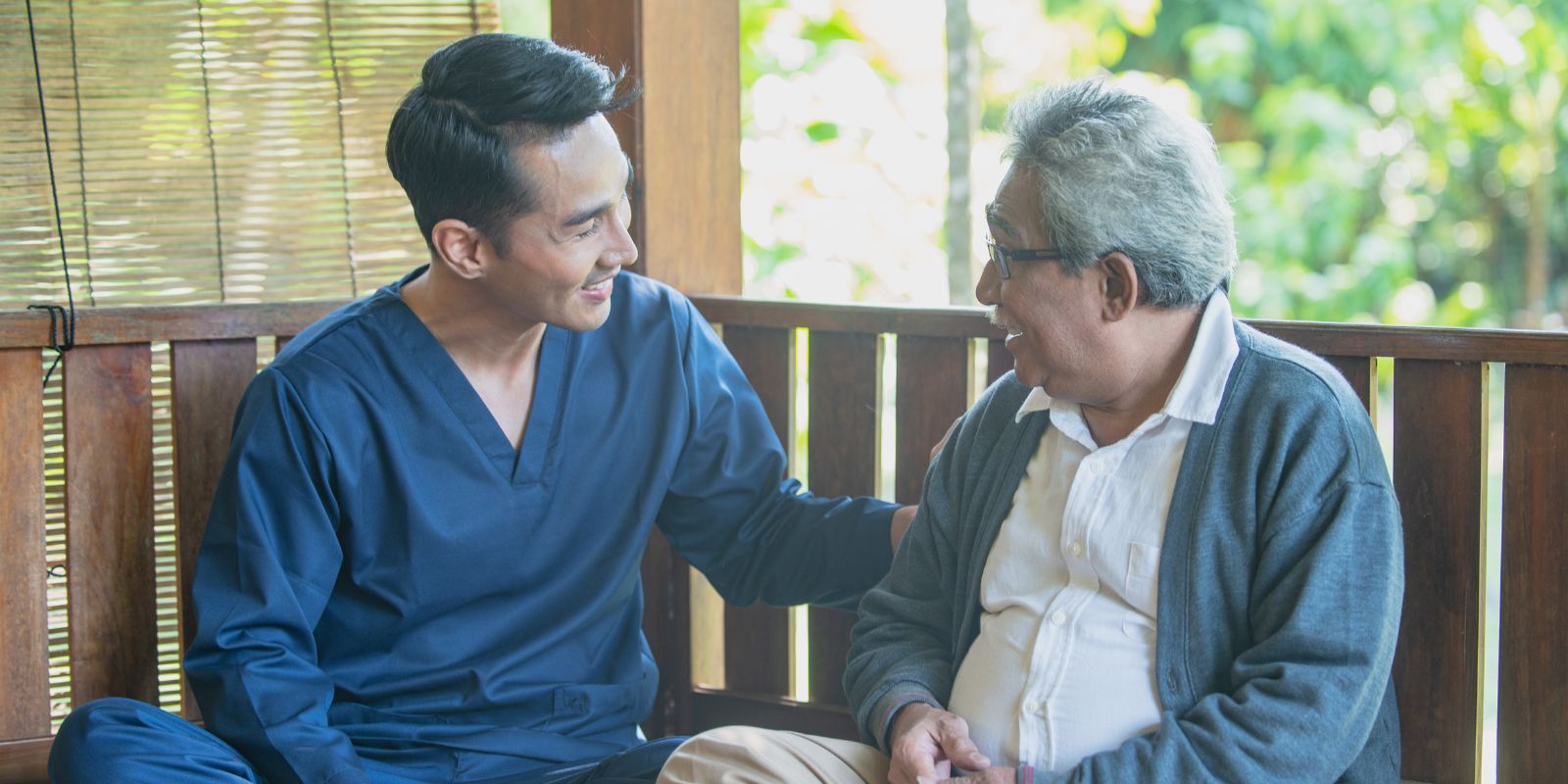 Two men sitting on a porch, smiling and talking over tea