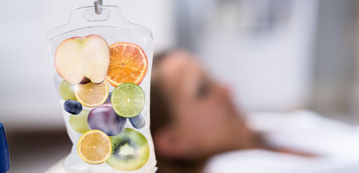 IV bag filled with assorted fruit slices hanging beside a blurred patient in a hospital bed