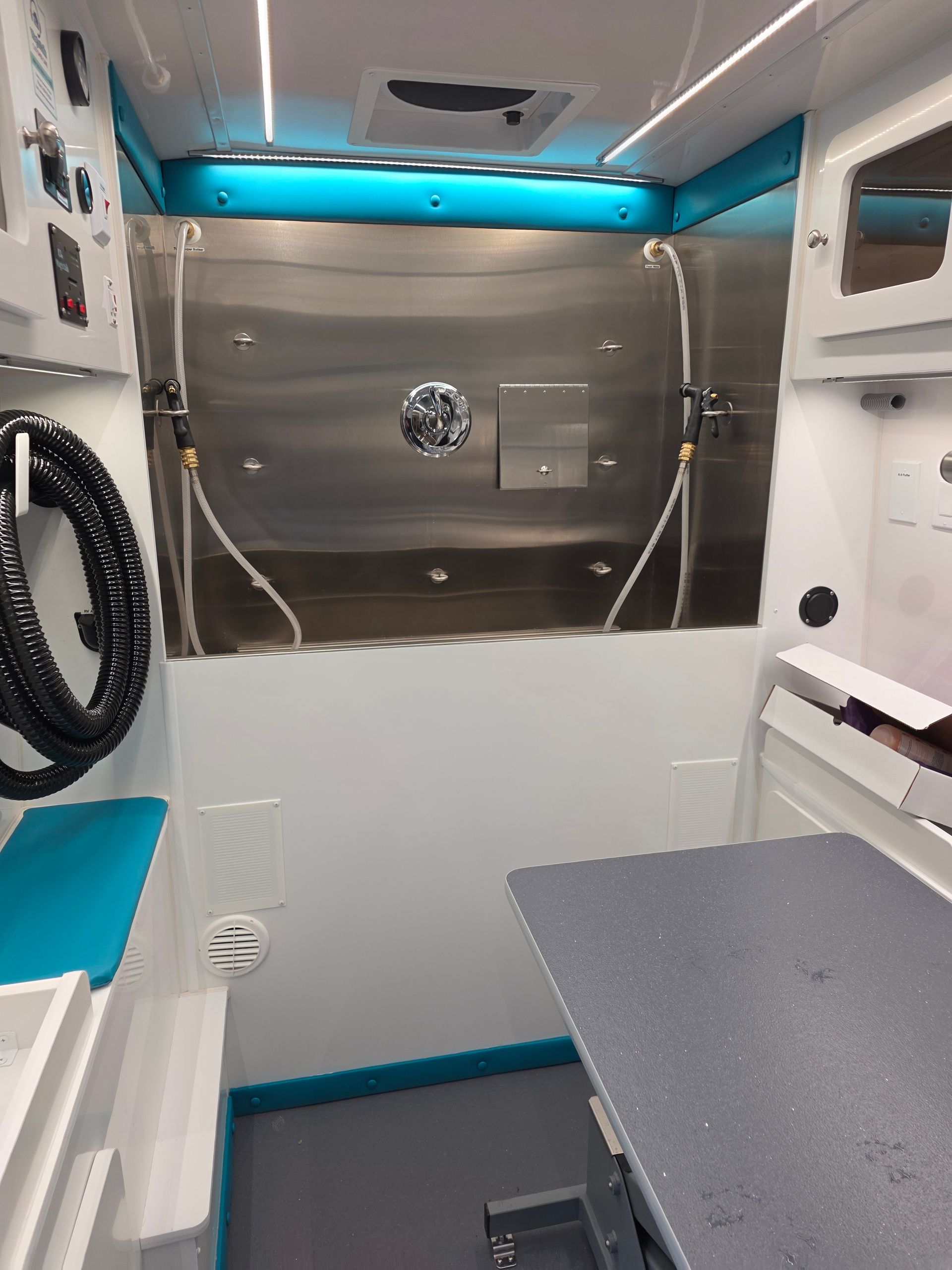 Inside of White van with blue and green branding for Sandy's Pet Spa, featuring a dog illustration, parked indoors.