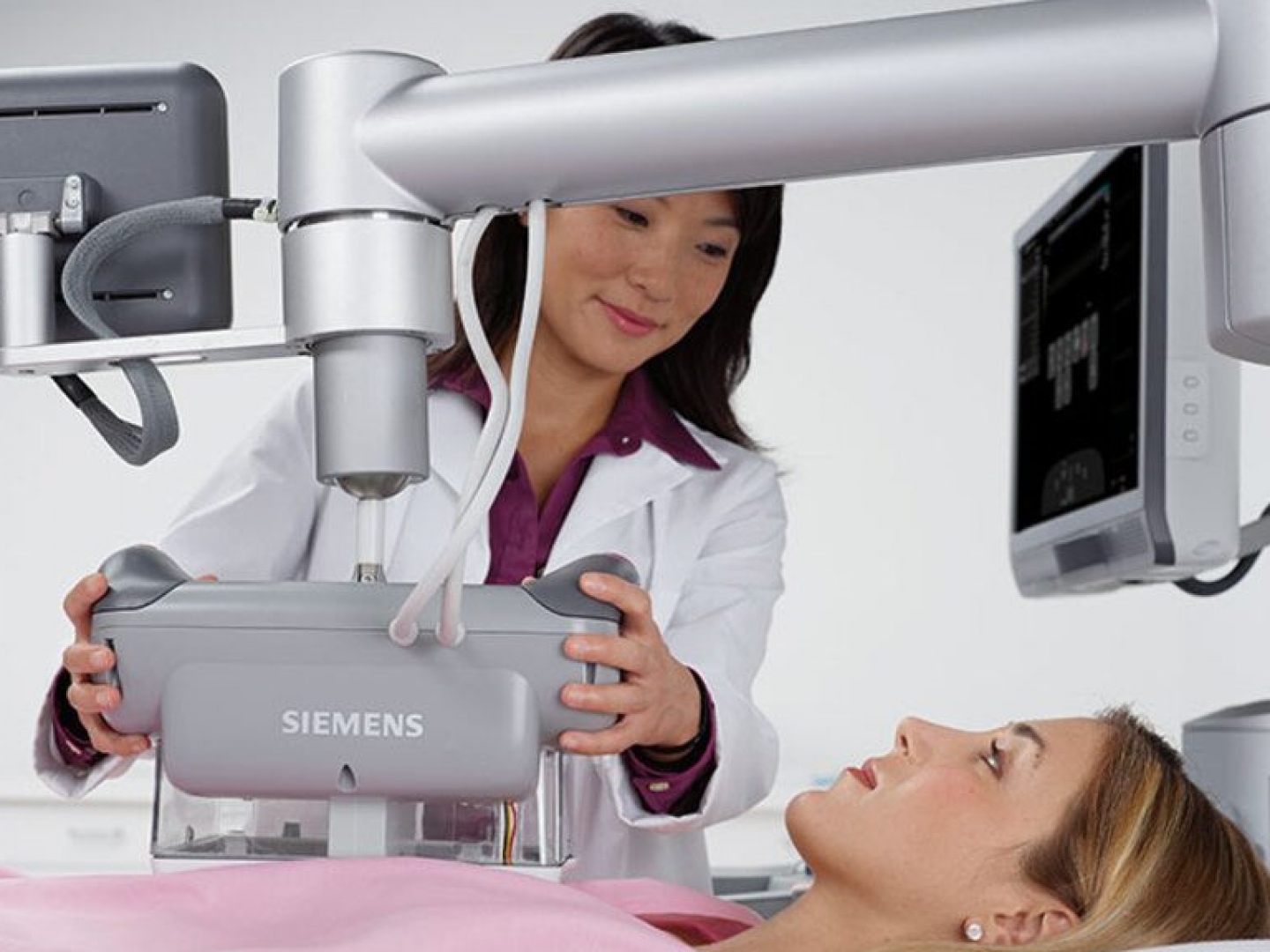 Technician operating a Siemens X-ray machine while a patient lies on the table