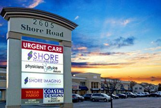 Shore Road medical center sign at sunset with urgent care, imaging, and office signs